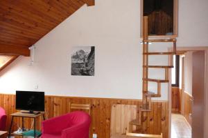 Le Mas du Plan في لو بورغ دوازو: غرفة معيشة بها كرسي احمر ودرج حلزوني