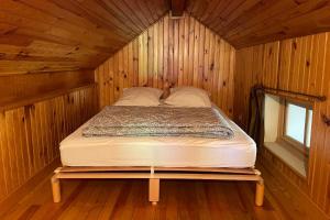 a bed in a wooden cabin with a window at Le Mas du Plan in Le Bourg-dʼOisans