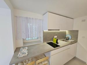 a kitchen with a sink and a counter with chairs at Apartman Velopin in Mali Lošinj