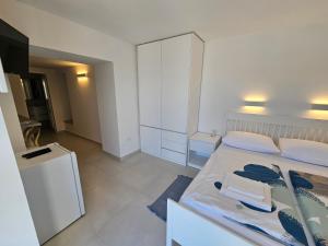 a white bedroom with a large bed with towels on it at Apartman Velopin in Mali Lošinj