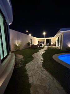 un patio trasero de una casa con piscina por la noche en HAFAL Resort شاليهات هافال, en Riad