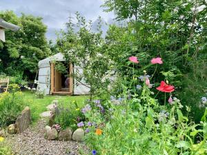 um jardim com flores e uma antiga caravana em The Croft Place of Architectual Interest em Lochearnhead