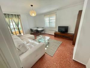 a living room with a white couch and a table at Villamar playa wifi y garaje in Cullera