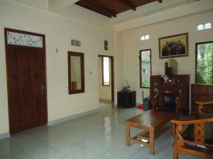 a living room with a door and a table and chairs at Kenari House in Ubud