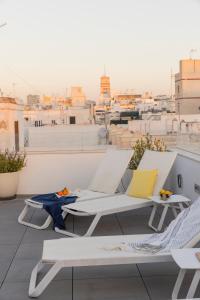 a balcony with white chairs and a view of a city at Candelaria10 in Cádiz