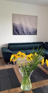 um vaso com flores amarelas numa mesa numa sala de estar em Lovely furnished 1 bedroom flat with balcony in Ostrava em Hrabŭvka
