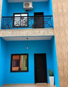 a blue building with a balcony and a black door at LUXURYs apartment in Abomey-Calavi
