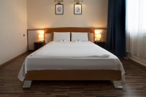 um quarto com uma cama grande e 2 candeeiros em Korona Hotel em Nyíregyháza