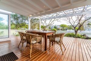 a wooden deck with a wooden table and chairs at Peaceful Parkland Home on Thesen Islands in Knysna