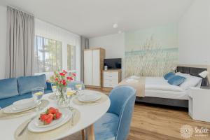 Seaside Apartamenty Dominikana Sianożęty Basen&Jakuzzi&Parking في سيانوزيتي: غرفة معيشة مع طاولة وكراسي زرقاء