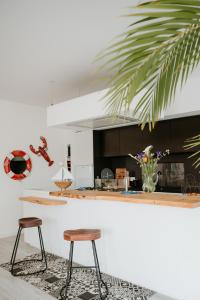 eine Küche mit zwei Barhockern und einer Theke in der Unterkunft La villa des dunes, 100 m de la mer, spa, sauna in Ploudalmézeau