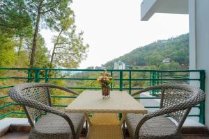 a table with two chairs and a vase of flowers on a balcony at The Kasauli Walk !! Top Rated & Most Awarded Property in Kasauli in Kasauli