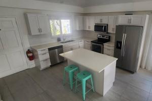 a kitchen with a refrigerator and two stools in it at Sunset Cove - Condo 314 in George Town