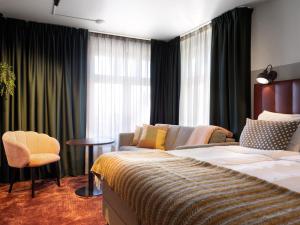 City Hotel Örebro في أوريبرو: غرفة نوم بسرير واريكة وكرسي