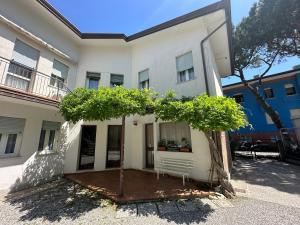 a white building with a tree in front of it at Casa Francesca - Agenzia Cocal in Caorle