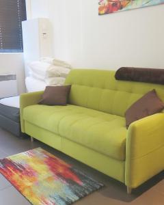 a yellow couch in a living room with a rug at Mini Loft Daval in Paris