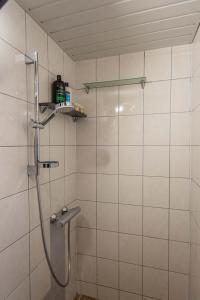a shower in a bathroom with white tiles at Preila Kristima-3 in Preila