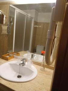 ein Badezimmer mit einem weißen Waschbecken und einem Spiegel in der Unterkunft Hotel Mairena in Mairena del Alcor