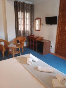 Habitación con cama, mesa y sillas. en Hotel Mairena, en Mairena del Alcor
