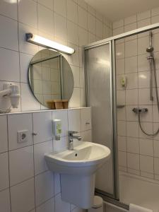 Baño blanco con lavabo y espejo en Hotel Brauhaus Bückeburg en Bückeburg