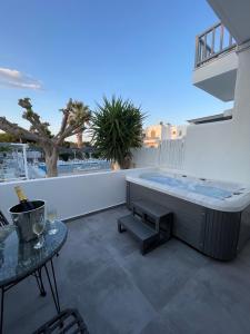 a hot tub on a balcony with a table at Zoumis Residence in Naousa