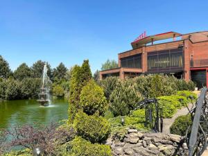 a building with a fountain in the middle of a pond at Via Baltica in Sargėnai