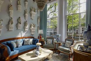 a living room with a blue couch and chairs at Pulitzer Amsterdam in Amsterdam