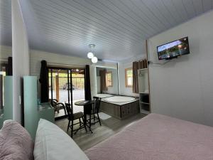 a living room with a bed and a tv on the wall at Pousada suite avencal in Urubici