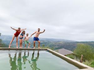 a family standing on the edge of a swimming pool at Mountain Log Cabin O Garrano in Cabeceiras de Basto