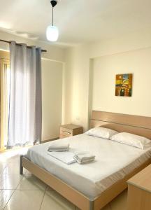 1 dormitorio con 1 cama grande con sábanas blancas en Deni Apartment, en Vlorë