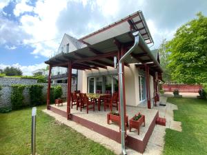 een pergola op een huis met een tafel en stoelen bij Gősy apartmanok in Siófok