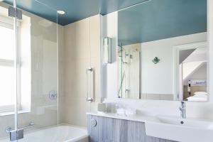 a bathroom with a tub and a sink and a mirror at Bournemouth Highcliff Marriott Hotel in Bournemouth