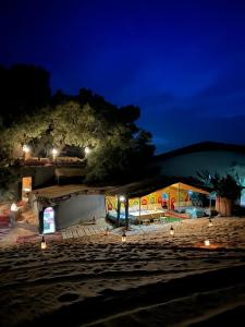 a building with lights on the beach at night at Tamaris Camp in Hassilabied