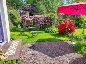 a red umbrella in a yard with chairs and flowers at Sanachan in Kishorn