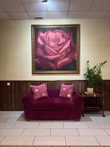 eine lila Couch in einem Zimmer mit einem Gemälde einer Rose in der Unterkunft Via Baltica in Sargėnai
