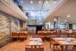 restauracja z drewnianymi stołami i krzesłami oraz schodami w obiekcie Hotel Jerez Centro w mieście Jerez de la Frontera