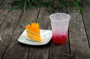 um pedaço de bolo num prato ao lado de uma bebida em Denchaicity Resort เด่นชัยซิตี้ รีสอร์ท em Phrae