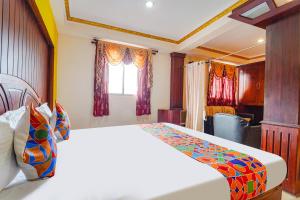 a bedroom with a bed and a window at FabHotel Roshan Residency Naidupuram in Kodaikānāl