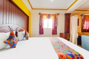 um quarto com uma cama grande e uma janela em FabHotel Roshan Residency Naidupuram em Kodaikanal