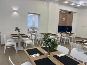 uma sala de jantar com mesas e cadeiras brancas em Hotel Dom Polonii em Ostróda