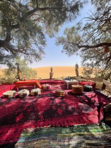 een rood bed met kussens op een tapijt bij Tamaris Camp in Adrouine