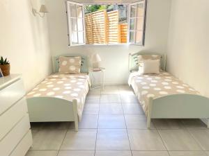two beds in a room with two windows at Maison au calme avec jardin et parking, proche de tout ! in La Ciotat