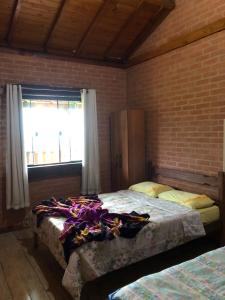 ein Schlafzimmer mit zwei Betten und einer Ziegelwand in der Unterkunft Chalé mirante da Serra rua E nova ibitipoca Lima Duarte MG in Ibitipoca