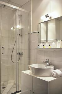 La salle de bains est pourvue d'une douche en verre et d'un lavabo. dans l'établissement Hôtel Du Centre Annemasse, à Annemasse