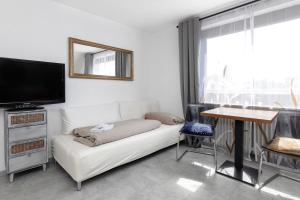 een woonkamer met een witte bank en een flatscreen-tv bij Pension Beermann in Wedemark