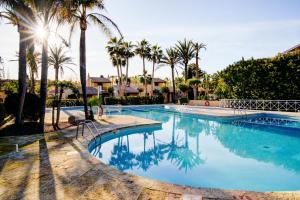 a swimming pool with palm trees in a resort at Ca Nura - Dúplex con piscina y a pasitos del mar in Son Xoriguer