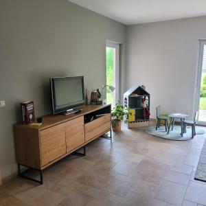 a living room with a flat screen tv on a wooden dresser at Ferienhaus Fliederhain in Stollberg