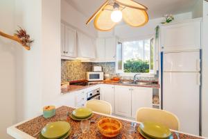 a kitchen with white cabinets and a table with chairs at Ca Nura - Dúplex con piscina y a pasitos del mar in Son Xoriguer