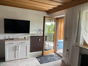 een woonkamer met een tv en een glazen schuifdeur bij Ferienwohnung Alpenblick in Bruckmühl