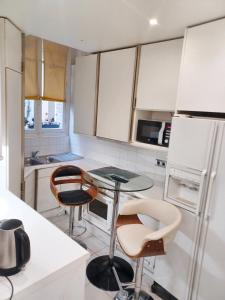 eine Küche mit weißen Schränken sowie einem Tisch und Stühlen in der Unterkunft Appartement d'une chambre avec wifi a ParisEL in Paris
